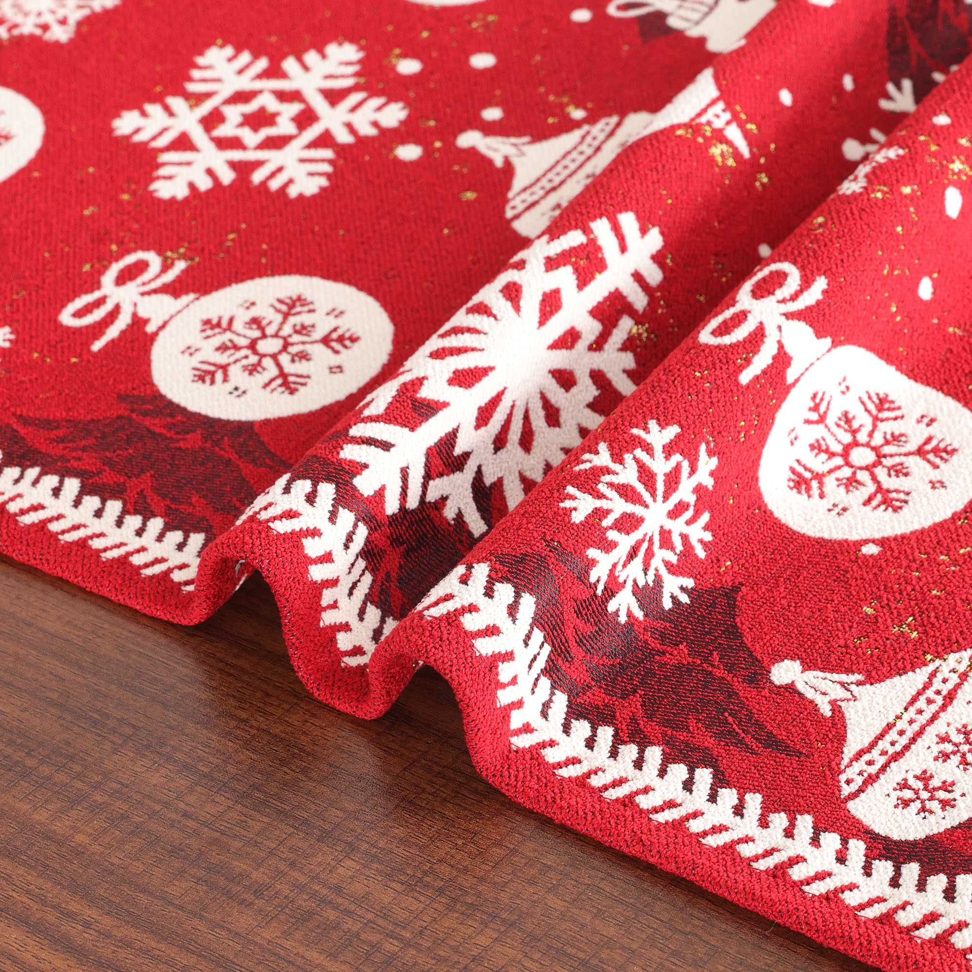 Dieses Bild zeigt die Details des Weihnachts-Tischläufers, besonders die weichen Falten am Rand. Der Tischläufer hat feine gewebte Muster und Schneeflocken, die die hohe Qualität der Jacquard-Webtechnik hervorheben. Der rote Hintergrund kontrastiert schön mit den weißen Mustern und verstärkt die festliche Atmosphäre. Die natürlichen Falten des Tischläufers betonen seine Weichheit und die präzise Verarbeitung, die jeder Tischdekoration Wärme und festliche Stimmung verleiht.