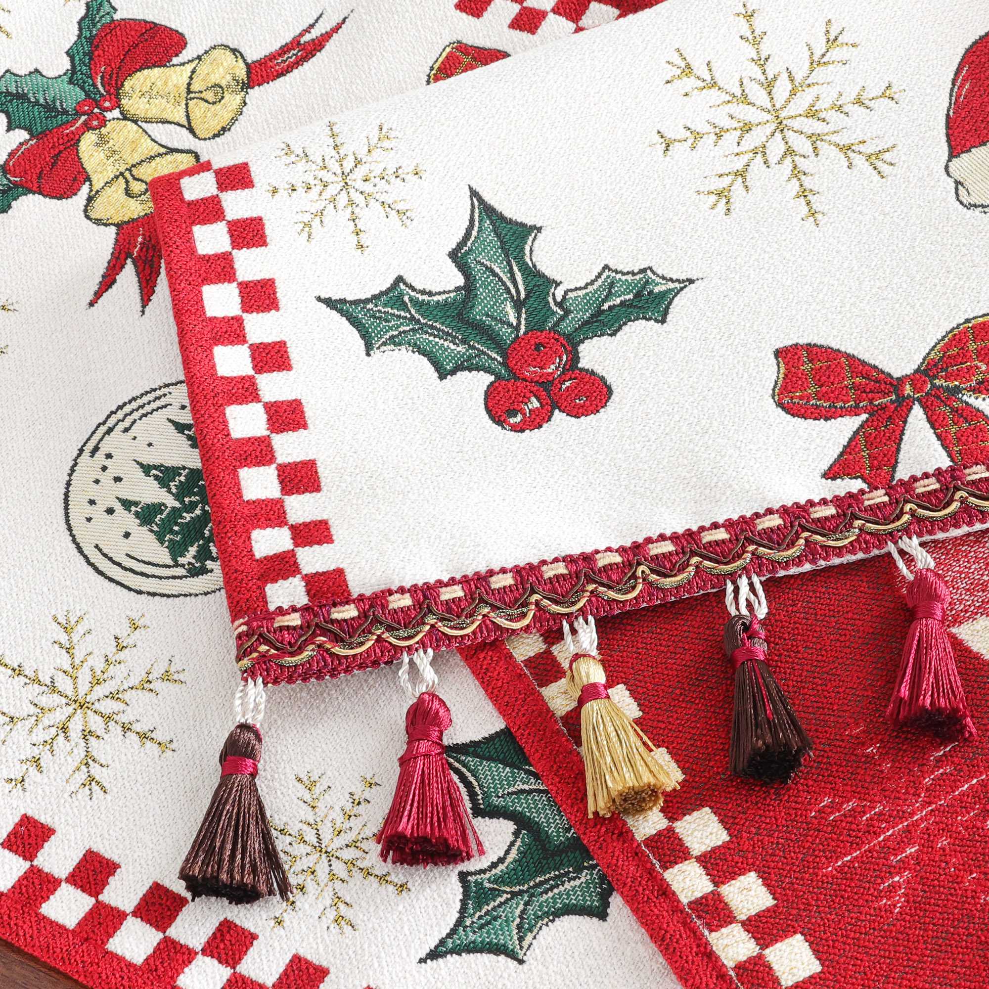 Dieses Bild zeigt die Details eines Weihnachts-Tischläufers mit festlichen Motiven wie Glocken, Weihnachtskugeln, Tannenzweigen und Schneeflocken. Der Tischläufer ist an den Rändern mit einem eleganten, farbigen Fransenbesatz verziert, der zusätzliche Festlichkeit und Charme verleiht. Der rot-weiße Rand sorgt für ein klassisches, weihnachtliches Aussehen, das perfekt in die Feiertagsdekoration passt und Ihrem Esstisch eine stilvolle Note verleiht.
